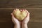Ugly food. kid`s hands holding ugly vegetable a heart shaped potato on a wooden plank table.