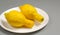 Ugly lemons on a white plate on a gray background.