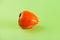 Ugly persimmon on green background with copy space. Intergrown double fruit. Funny, unnormal vegetable or food waste concept