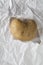 Ugly potato in the heart shape on crumpled craft white paper