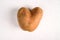 Ugly potato in the shape of a heart on a gray background.