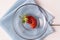 Ugly strawberry on a plate on a wooden background