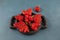 Ugly strawberry. Unusual fruits shape. Berries in a wooden plate on a blue background. Top view