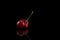 Ugly weird red sweet cherry cherries on black background. Side view, close up, copy space. Trendy food