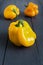 Ugly yellow bell peppers deformed shaped on the wooden gray background. Trendy misshapen food.