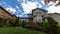 UHD movie of moving clouds and blue sky over suburb home with manicured lawn and garden