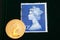 UK blue stamp with portrait of Elizabeth II and 1980 Australian Gold sovereign on black background