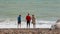 UK, Brighton. Three young pupils on summer vacation standing on the beach near the water of Atlantic ocean. Friends wet