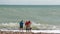 UK, Brighton. Young couple and friend are on the shore of Atlantic ocean. A couple is hugging, a girl is standing side