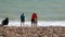 UK, Brighton. Young couple and a young woman are on the shore of Atlantic ocean. A couple is hugging, a girl is standing