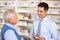 UK pharmacist serving senior man in pharmacy