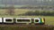 Uk railroad next to rapeseed field and sheep on another side under overcast rain. railway landscape