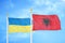 Ukraine and Albania two flags on flagpoles and blue sky