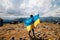 UKRAINE - August 24. 2019. Patriot woman stands with national Ukrainian flag and waving it praying for peace at top of Hoverla