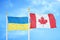 Ukraine and Canada two flags on flagpoles and blue sky