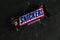 Ukraine, Chernihiv, June 23, 2022: Chocolate bar snickers in branded packaging close up on a dark background