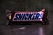 Ukraine, Chernihiv, June 23, 2022: Chocolate bar snickers in branded packaging close up on a dark background