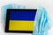 Ukraine flag covered by surgical protective mask for coronavirus COVID-19 prevention.