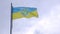 Ukraine flag with trident on a blue sky background at windy day.