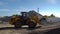 UKRAINE. Huge piles of crushed stones and sand outdoors. Bulldozer working on the territory of asphalt plant in a sunny