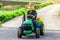 Ukraine Kiev 4 May 2019.A child on his little tractor John Deere .Portrait of young boy in nature, park or outdoors.Happy smiling