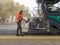 Ukraine, Kiev - September 22, 2019. Workers regulate the laying of tracked pavers, asphalt, heated to high temperatures on runway