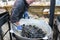 UKRAINE, LUTSK - June 5, 2019: Man is cooking a fresh mussels in shells in large metallic grill pan on a food fest.