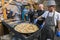 UKRAINE, LUTSK - June 5, 2019: Man is cooking a fresh mussels in shells in large metallic grill pan on a food fest.