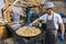 UKRAINE, LUTSK - June 5, 2019: Man is cooking a fresh mussels in shells in large metallic grill pan on a food fest.