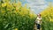 Ukraine, Lviv region, a cute happy boy runs happily among rapeseed in a rapeseed field with the great-grandfather of