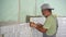 Ukraine, Mariupol - September 1, 2020. Worker lays the white ceramic tile on the kitchen wall. Professional tiler