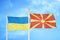 Ukraine and North Macedonia two flags on flagpoles and blue sky