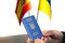 Ukrainian biometric passport in the hands of an elderly man against the background of the Ukrainian and Spanish flags