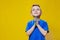 Ukrainian boy prays for Ukraine. Children against war. A boy in a blue T-shirt on a yellow background folded his hands