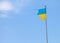 Ukrainian damaged flag against blue sky