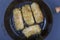 Ukrainian dishes - homemade stuffed cabbage rolls with rice and meat in tomato sauce in a frying pan on a black slate background,