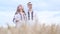 A Ukrainian family in embroidered dresses sings a song in the middle of a wheat field.