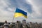 Ukrainian flag in the hands of a man standing on the roof of a house in Kyiv above the buildings