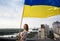 Ukrainian flag in the hands of a woman standing on the roof of a house in Kyiv above the buildings