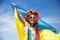 Ukrainian girl carries blue and yellow flag of Ukraine fluttering on the blue sky background