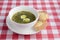 Ukrainian green borsch with boiled eggs served in white plate over red plad table cloth