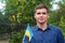 Ukrainian man. Young smiling man holding ukrainian flag. No war. Support for Ukraine. Patriotic Spirit rising hand of Ukraine flag