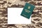 Ukrainian military ID and blank paper sheet on fabric with texture of pixeled camouflage. Cloth with camo pattern in grey, brown