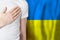 Ukrainian person with hand on heart on the background of Ukraine flag. Patriotism, country, national, pride concept