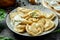 Ukrainian or Polish traditional dish - Pierogi or Varenyky dumplings stuffed with spinach and cheese and sour cream on a dark