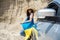 Ukrainian pretty girl with national flag posing in a sand quarry near the car