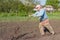 Ukrainian senior peasant working with hand plough in kitchen garden