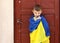 Ukrainian small child stands outdoors supporting homeland, little kid covered in national flag looking at camera