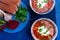 Ukrainian traditional borsch. Russian vegetarian red soup in blue bowl on blue wooden background. Borscht, borshch with beet. Tw