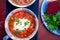 Ukrainian traditional borsch. Russian vegetarian red soup in blue bowl on red wooden background. Borscht, borshch with beet. Two